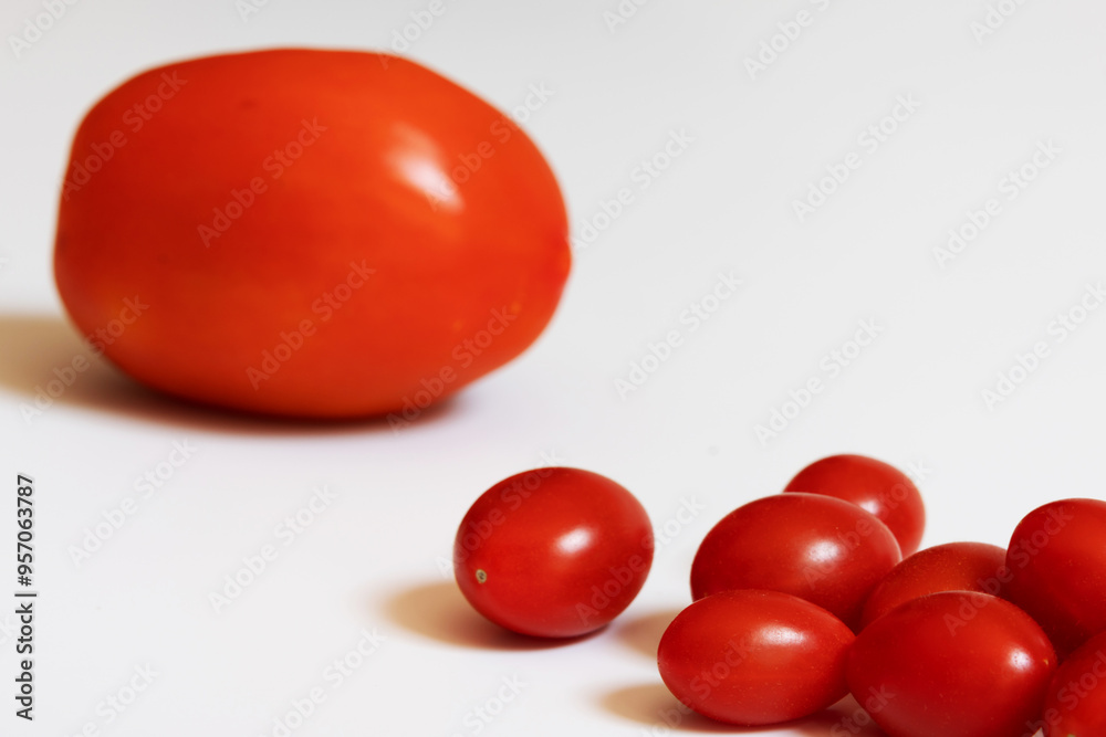 Portion of cherry tomatoes in the foreground on the right of the image and an Italian tomato in the background out of focus on the left of the image Portion of cherry tomatoes in the foreground on the right of the image and an Italian tomato in the background out of focus on the left of the image