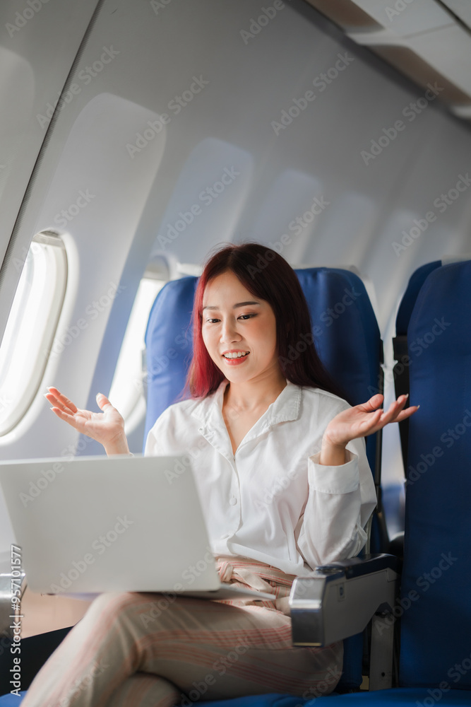 Businesswoman Working on Laptop in Airplane: A confident businesswoman with red hair, seated in an airplane, works on her laptop, showcasing the modern professional who stays productive while travelin Businesswoman Working on Laptop in Airplane: A confident businesswoman with red hair, seated in an airplane, works on her laptop, showcasing the modern professional who stays productive while travelin