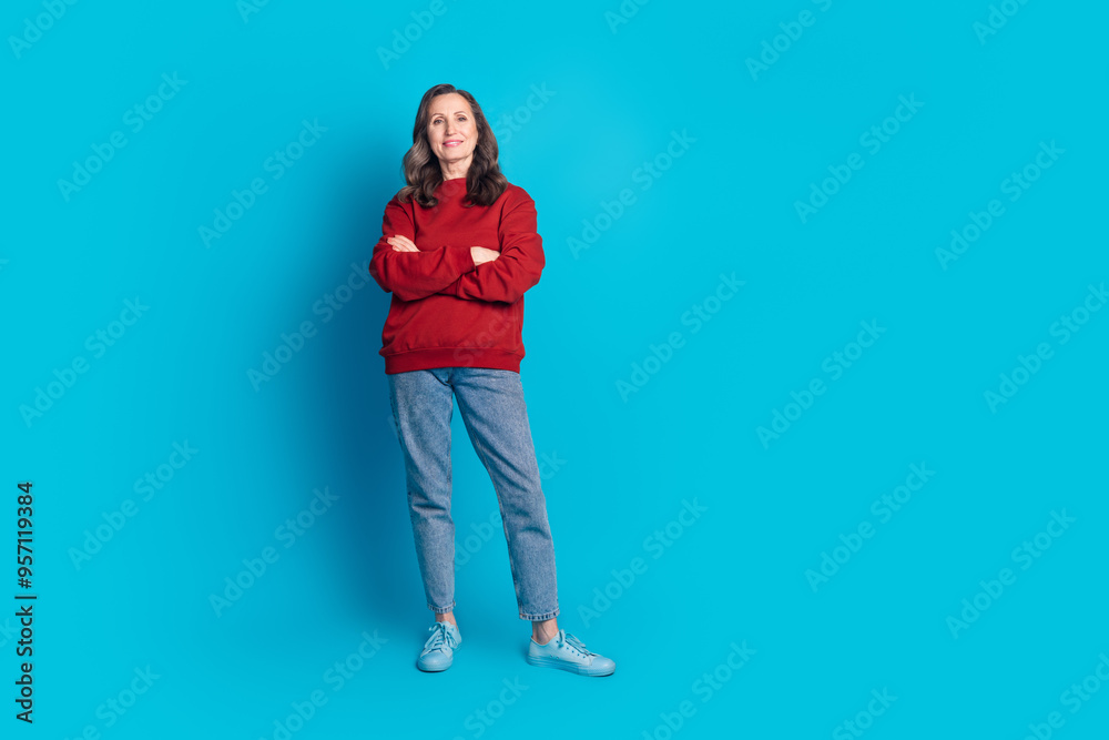 Full size photo of pretty aged lady folded arms empty space wear pullover isolated on blue color background Full size photo of pretty aged lady folded arms empty space wear pullover isolated on blue color background