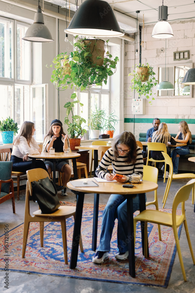 Student at table near other blurred visitors in cafe Student at table near other blurred visitors in cafe