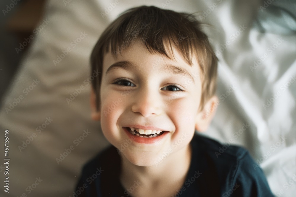 A joyful child beams at the camera, lying against a pillow with messy hair, conveying pure happiness and innocence. A joyful child beams at the camera, lying against a pillow with messy hair, conveying pure happiness and innocence.