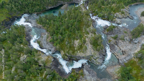 Sunning view of big waterfall, aerial photo of forest waterfall from Norway nature landscape scenery with green forest and blue water.