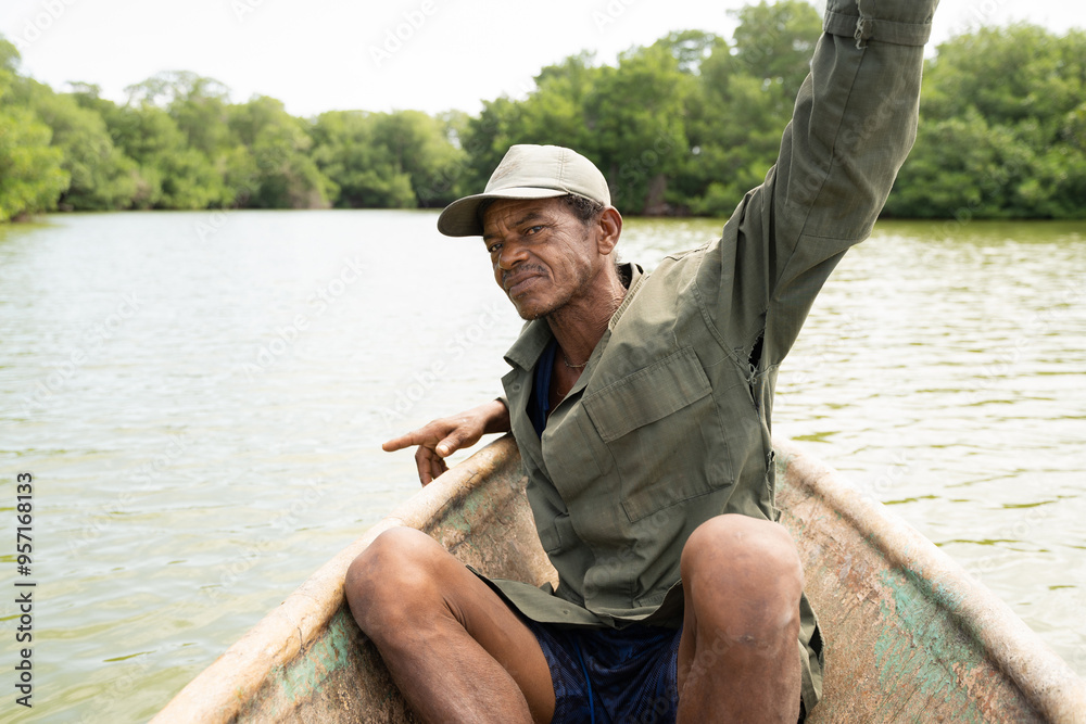 Hispanic man with his arm raised in a canoe on a river Hispanic man with his arm raised in a canoe on a river