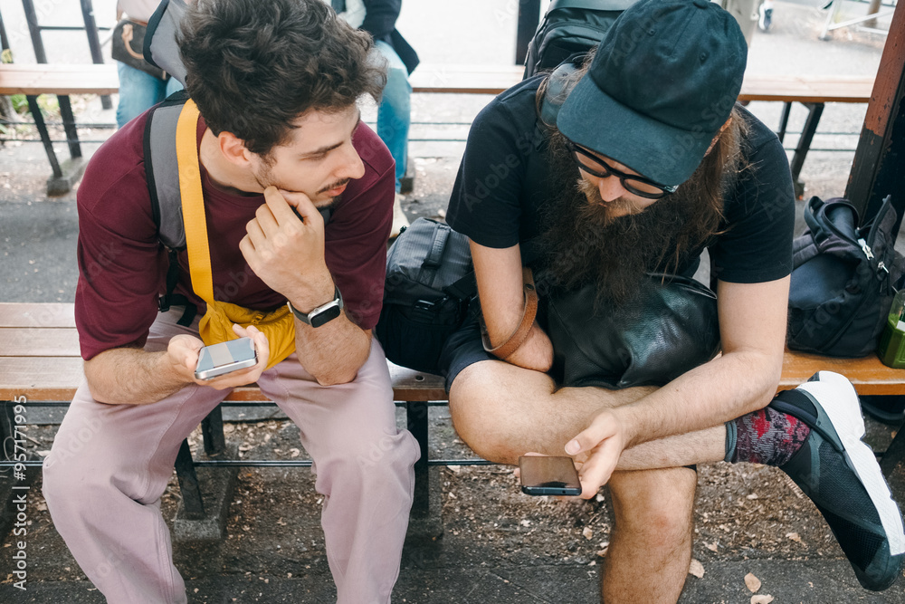 Friends sitting on a bench and looking at mobile phone