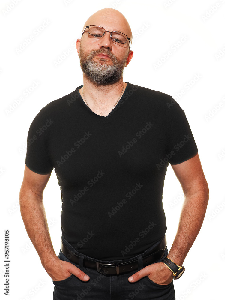 Portrait of a man in his 40s or 50s. Model is bald with grey beard in black shirt which shows his slim athletic body wearing glasses. White background. Healthy male posing. Hands in pockets. Portrait of a man in his 40s or 50s. Model is bald with grey beard in black shirt which shows his slim athletic body wearing glasses. White background. Healthy male posing. Hands in pockets.