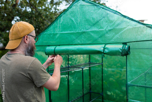 a man unscrews the entrance to a greenhouse