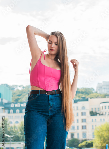 Youth concept. Nice beautiful Slavic beauty with long blonde hair, girl in pink top and jeans outdoor portrait