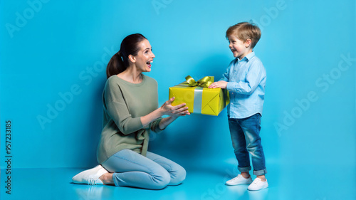 Happy mother and son with a gift box on a blue background.