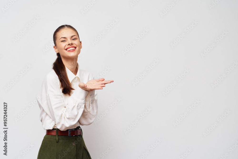 Smiling woman in a white blouse and green skirt, presenting with her hands on a light gray background Joyful expression, professional look, engaging demeanor, perfect for business context Smiling woman in a white blouse and green skirt, presenting with her hands on a light gray background Joyful expression, professional look, engaging demeanor, perfect for business context