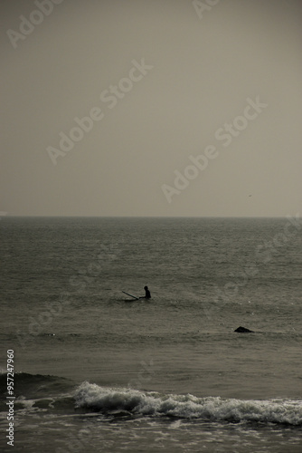 Surfer sitting calmly on their board, poised and relaxed.