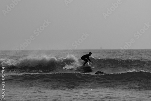 Black and white silhouette of a surfer catching a wave.