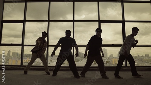 Silhouette shot of skilled choreographer group dancing together with sky scrapper, cityscape background. Young hipster team dancing performance. Sepia filter. Shadow. Outdoor sport 2024. Hiphop. photo