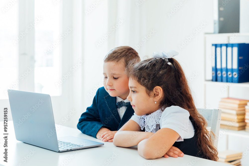 Boy and girl schoolgirl studying at a table with a laptop Boy and girl schoolgirl studying at a table with a laptop