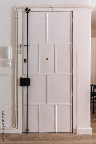 A white, paneled door equipped with a black security bar photo