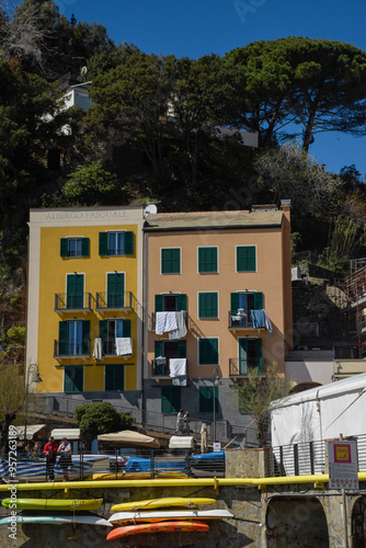 Vibrant urban scene featuring two colorful buildings—one painted yellow and the other light pink— with clothes hanging out to dry over the windows. 