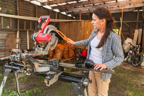 Focused Woman Cleaning Table Saw in Garage Workshop photo