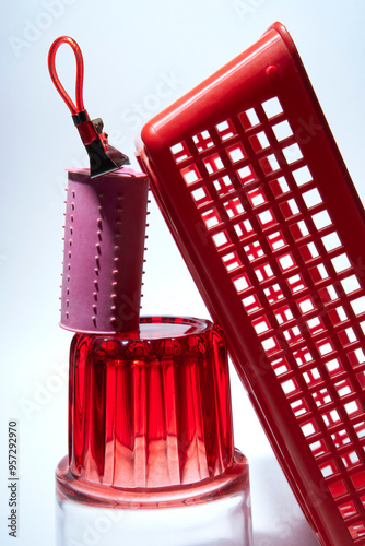 Red Plastic Basket, Pink Hair Roller, and Glass on White Background photo