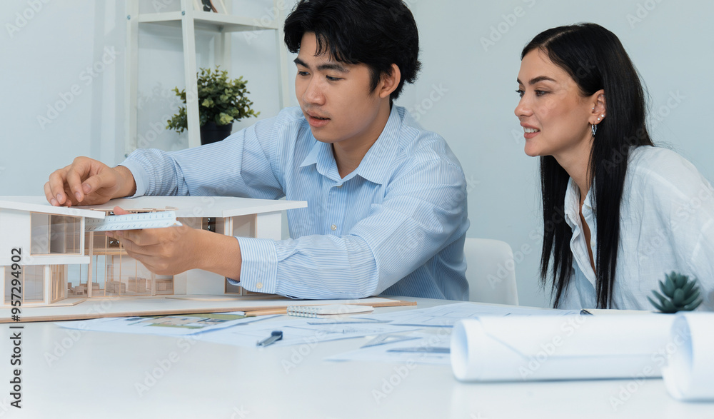 Portrait of cooperative engineer team working together to measure house model by using ruler and architectural equipment. Creative business design and teamwork concept. Immaculate.. Portrait of cooperative engineer team working together to measure house model by using ruler and architectural equipment. Creative business design and teamwork concept. Immaculate..