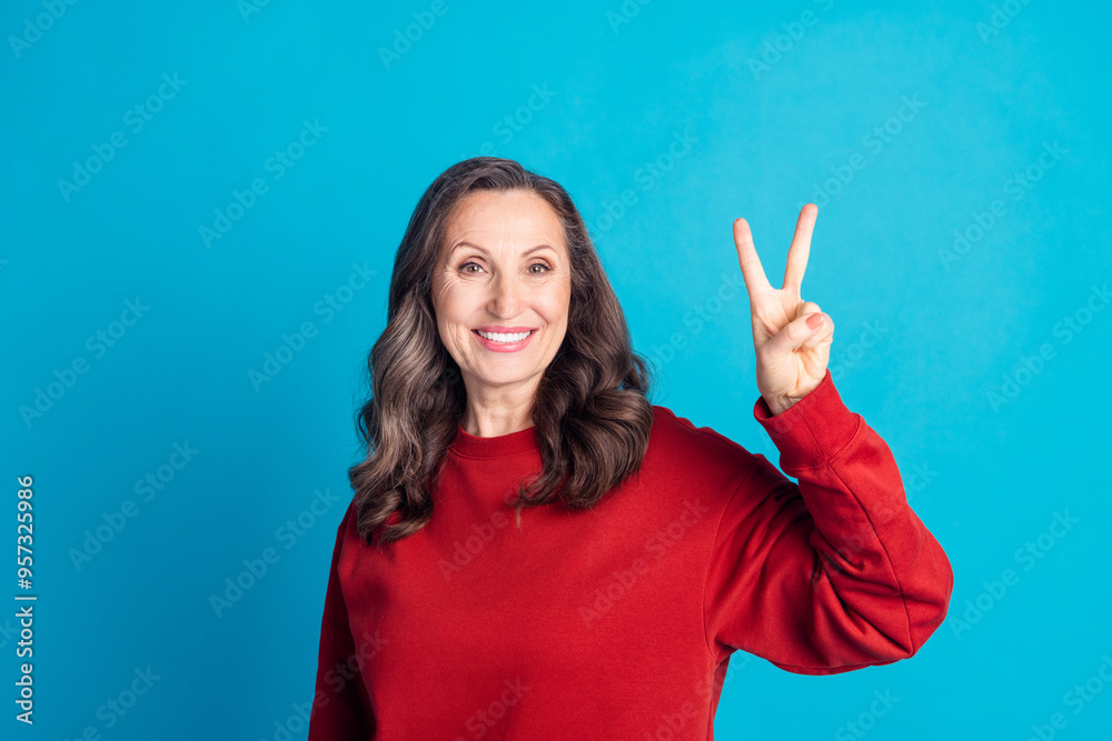 Photo of pretty aged lady demonstrate v-sign wear red pullover isolated on blue color background