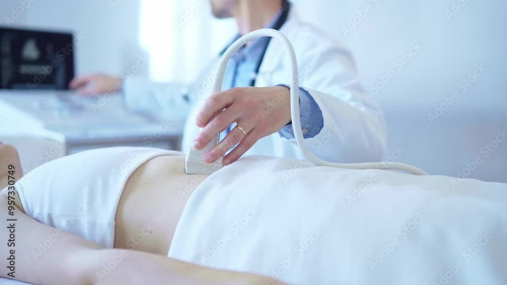 Doctor man wearing a white coat using an ultrasound machine on a female patient examining internal organs. Preventive therapy in medicine Doctor man wearing a white coat using an ultrasound machine on a female patient examining internal organs. Preventive therapy in medicine