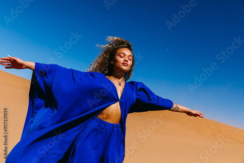 Woman in Blue Clothing Posing in Desert Landscape Under Bright Blue Sk photo