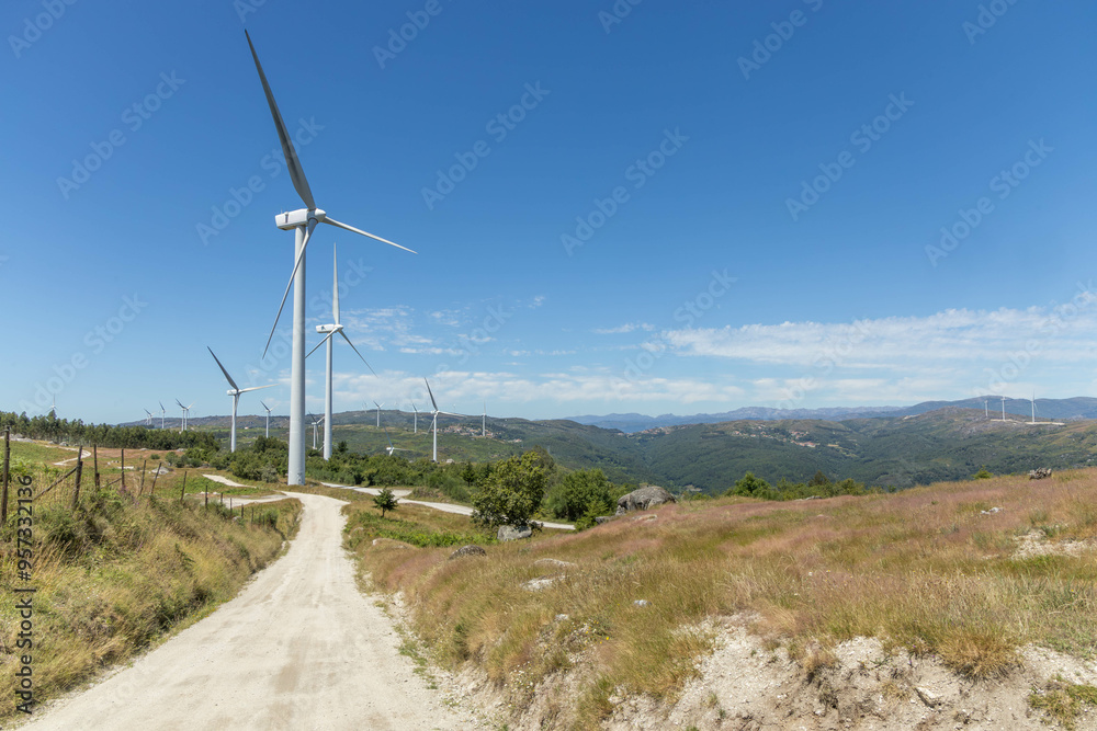 Large modern windmills on the mountains with deserted road and blue sky in the Fafe region of Portugal Large modern windmills on the mountains with deserted road and blue sky in the Fafe region of Portugal