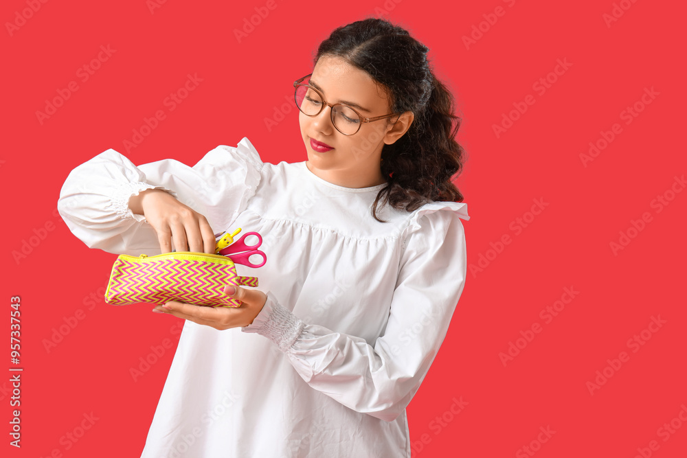 Female student with pencil case on red background Female student with pencil case on red background