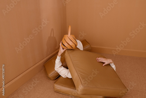 Person Playfully Hidden Among Tan Cushions in Minimalist Room