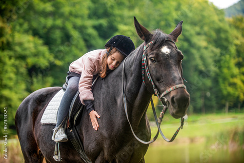 Child girl rides horse on the outdoors in the middle of the forest, park, trees, mountains. Girl on a horse in the forest. Horseback riding, lovely equestrian. Little girl riding a horse