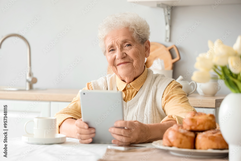 Senior woman using tablet computer at table in kitchen Senior woman using tablet computer at table in kitchen