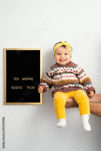 Ten months old baby in her father's hand next to development chart photo