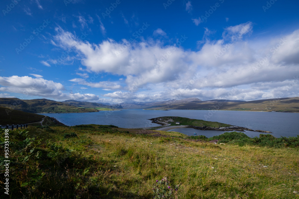The image shows a body of water surrounded by grass and hills in a natural landscape in Scotland. It captures a serene outdoor scene with a cloudy sky. The image shows a body of water surrounded by grass and hills in a natural landscape in Scotland. It captures a serene outdoor scene with a cloudy sky.