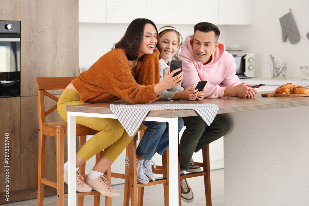 Happy family with mobile phones resting at table in kitchen Happy family with mobile phones resting at table in kitchen