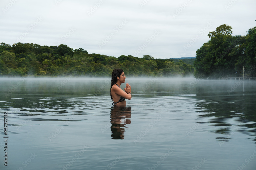 woman stands peacefully in the calm waters of a misty lake meditating woman stands peacefully in the calm waters of a misty lake meditating