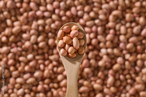 Wooden Spoon Holding Peanuts Against Blurred Background