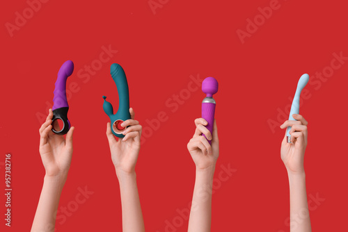 Female hands with different vibrators on red background