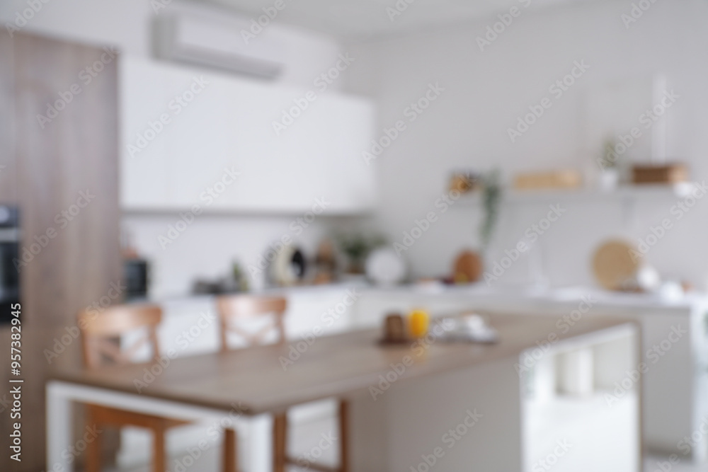 Fototapeta premium Blurred view of light kitchen with counters, table and plants