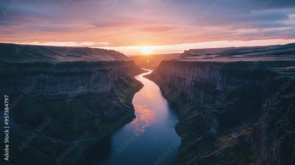 Fototapeta premium The sun descends beyond a canyon, where a river meanders between the distant mountain range