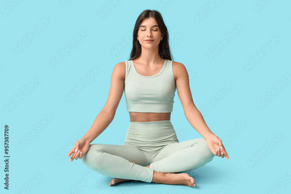 Sporty young woman meditating on blue background Sporty young woman meditating on blue background
