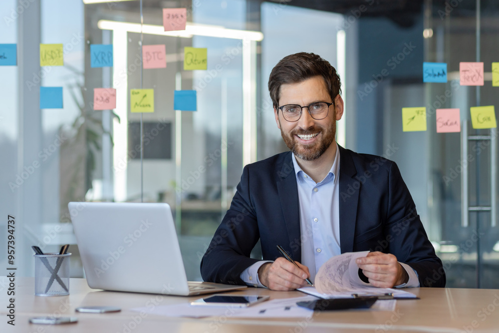 Smiling businessman working with documents in modern office setting Smiling businessman working with documents in modern office setting