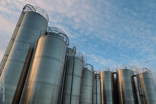 A row of large tanks are lined up against a blue sky photo