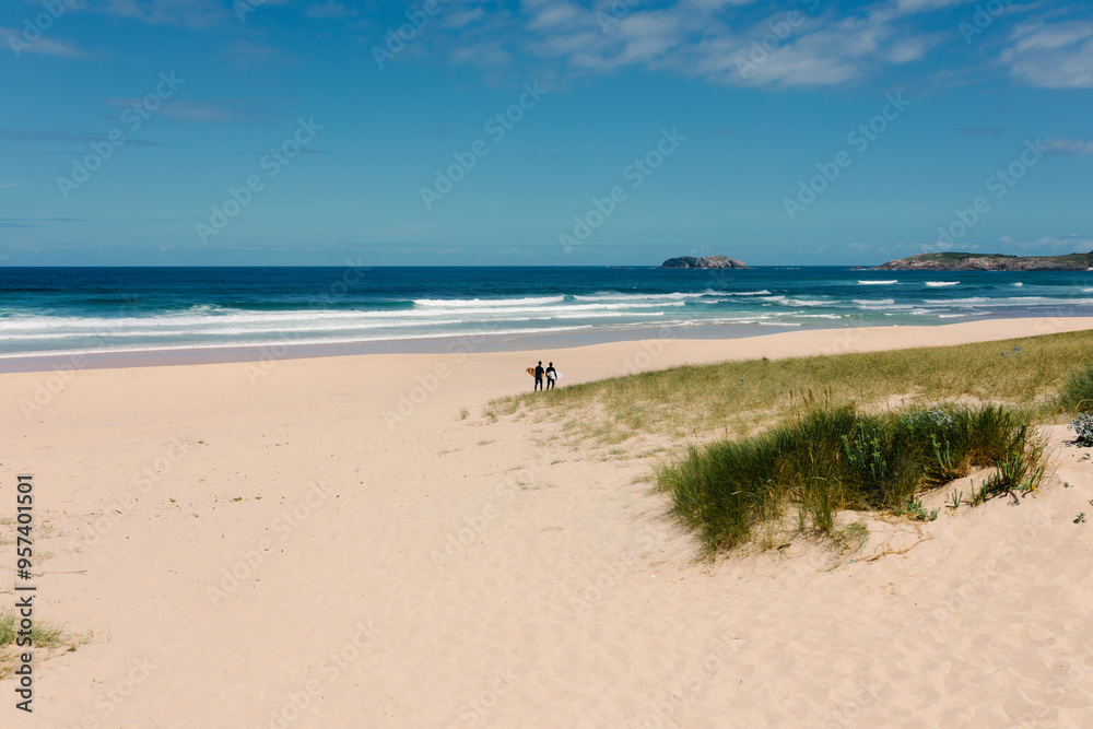 Long shot depicts surfers strolling in the distance on Doniños beach Long shot depicts surfers strolling in the distance on Doniños beach
