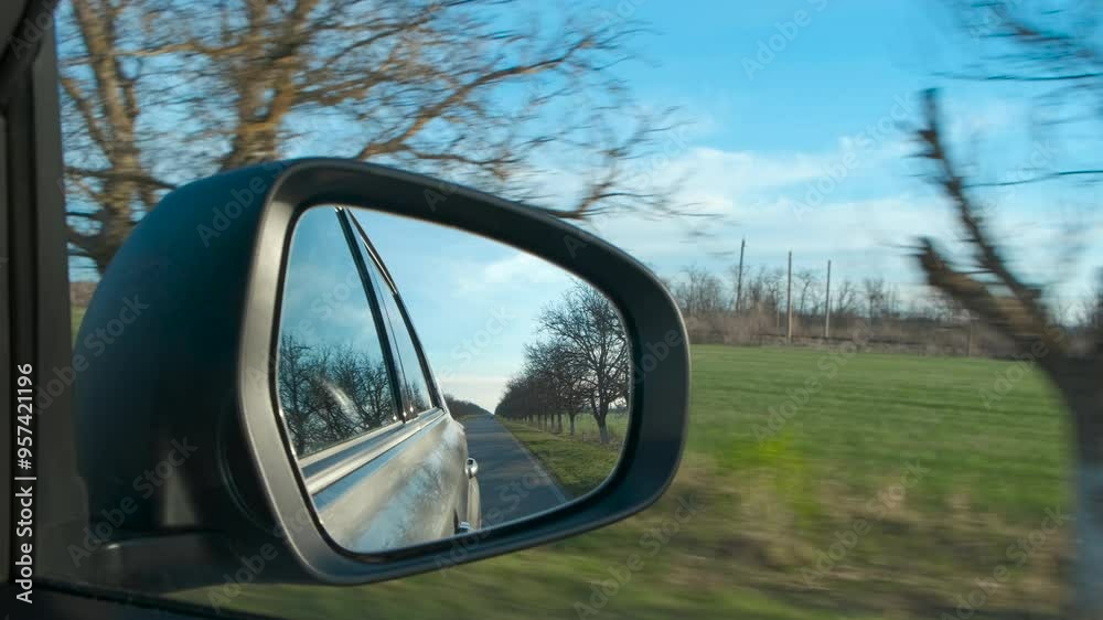 Green country road in the rear view mirror of auto. A view of green country road reflected in the rearview mirror of the driving car. Green country road in the rear view mirror of auto. A view of green country road reflected in the rearview mirror of the driving car.