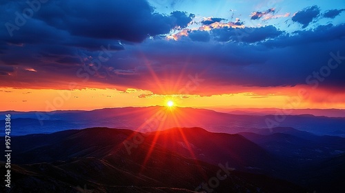  Sun setting on mountain range in the distance with foreground mountains and clouds in the background