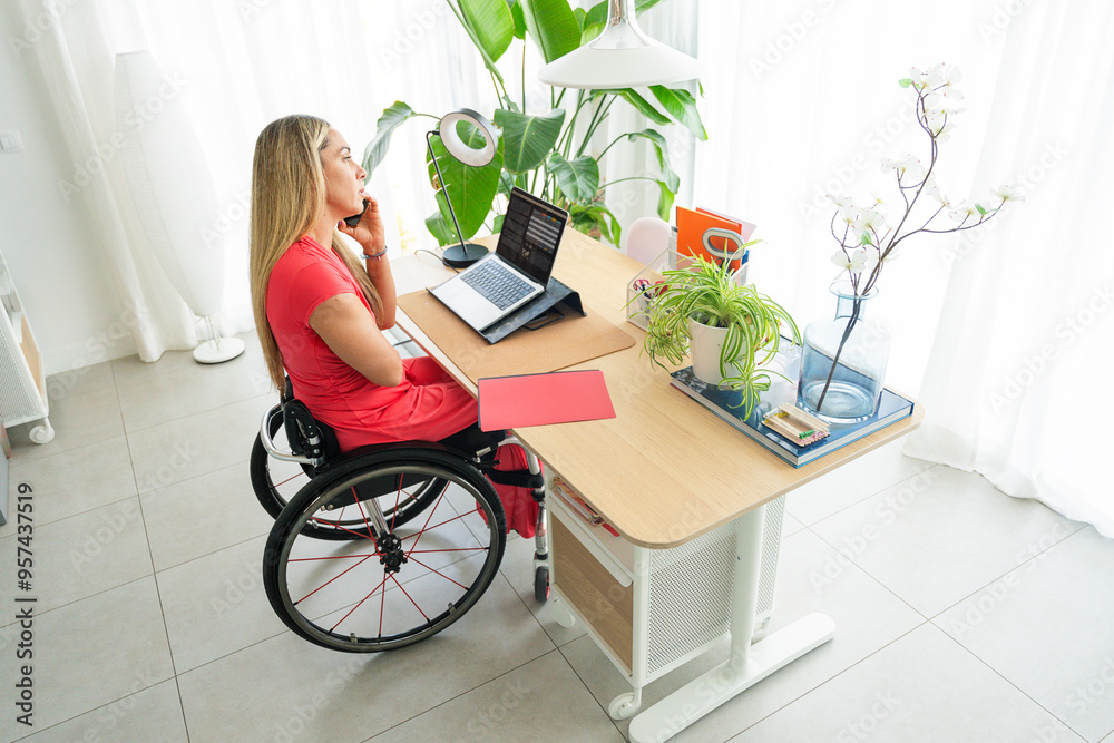 Person in wheelchair talking on phone in home office Person in wheelchair talking on phone in home office