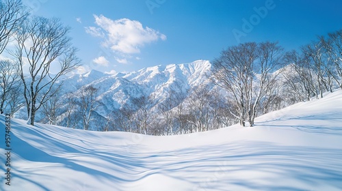  A breathtaking image of a snow-capped mountain surrounded by lush trees in the foreground, set against a serene blue sky with fluffy white clouds in the backdrop