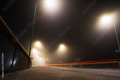 Foggy road and car taillights on bridge over Pirita River at night in autumn. photo