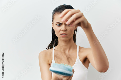 Hair loss, concern, beauty routine, woman with hairbrush, negative emotions, health awareness, stress reaction, white background, close up image of a female figure