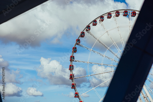 Ferris Wheel with Red Gondolas Against Blue Sky