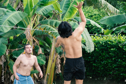 Group of Young Adults Playing Volleyball in Tropical Field photo